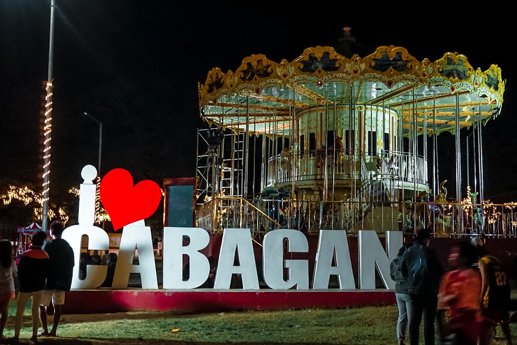 A town sign with a lit carousel at the back