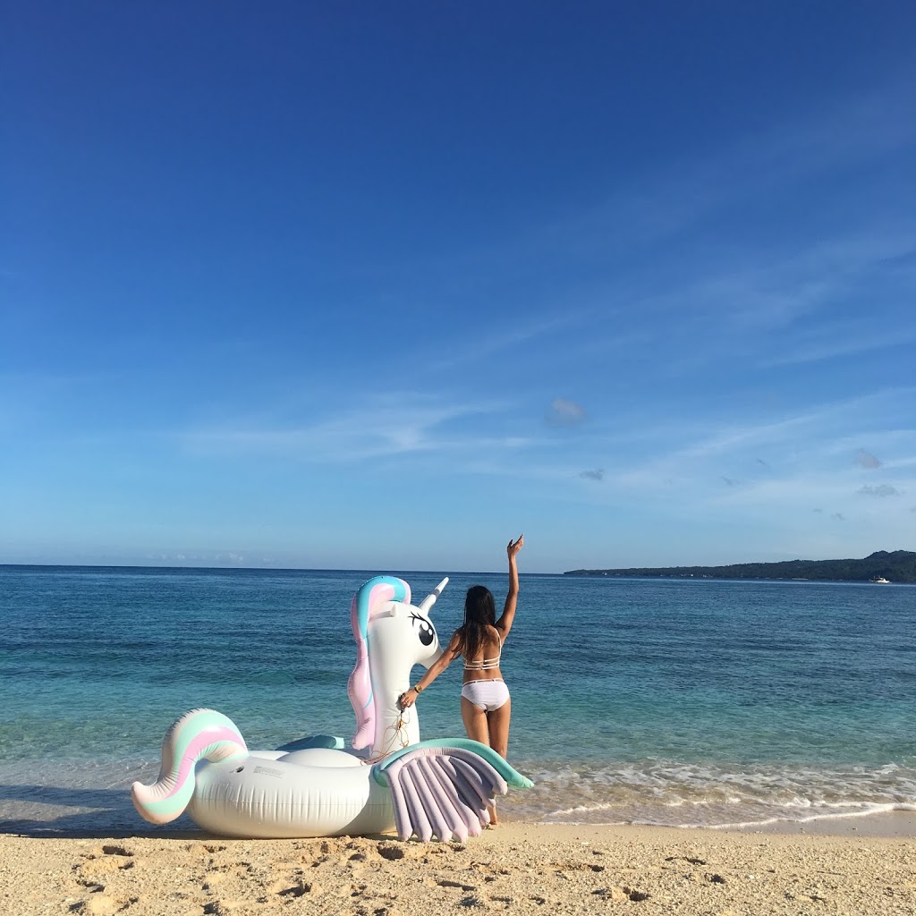 a girl with a unicorn floater at the beach