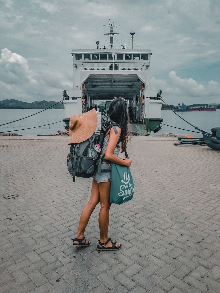 a lady with a backpack on its back facing a ferry