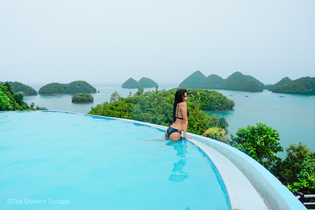 a girl at the edge of the pool overlooking a lake with islets