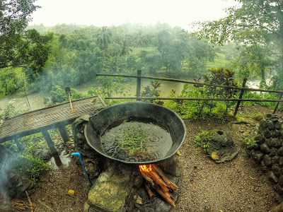 a giant wok on fire at the edge overlooking a river