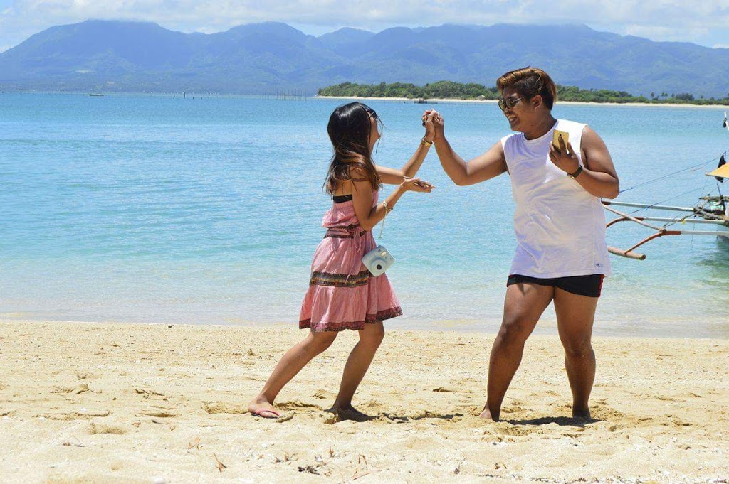 A boy and a girl joining hands for a high five at a beach